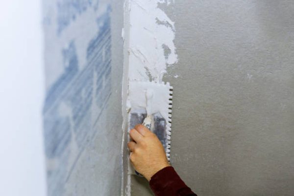 Handyman applying ceramic tiles on bathroom walls in bathroom during renovation